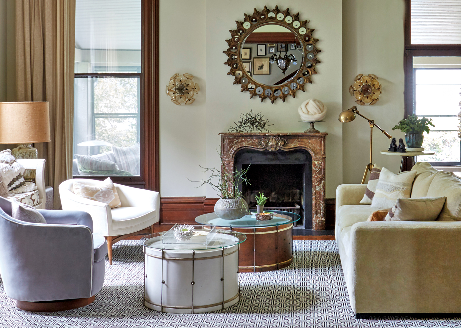 Living room with circular coffee tables, ornate sunburst mirror and a stone fireplace
