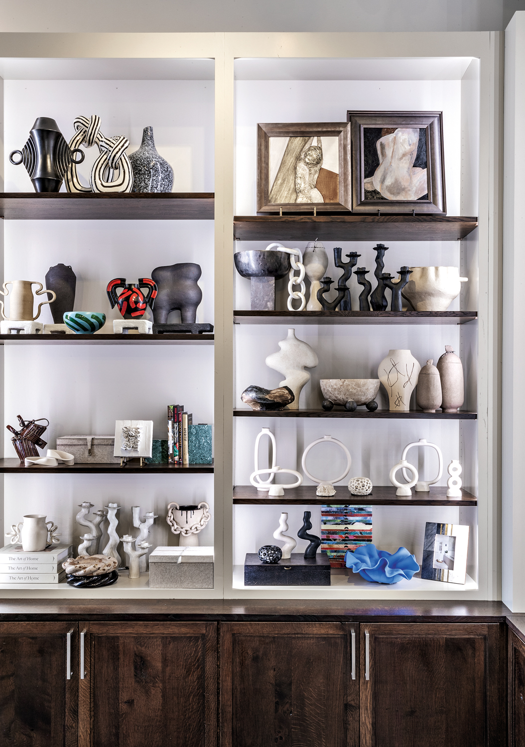 Shelves filled with black and white vessels, framed artwork and sculptures