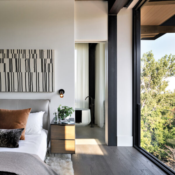 bedroom suite with a grey headboard with abstract artwork above it, wooden night stand and white rug