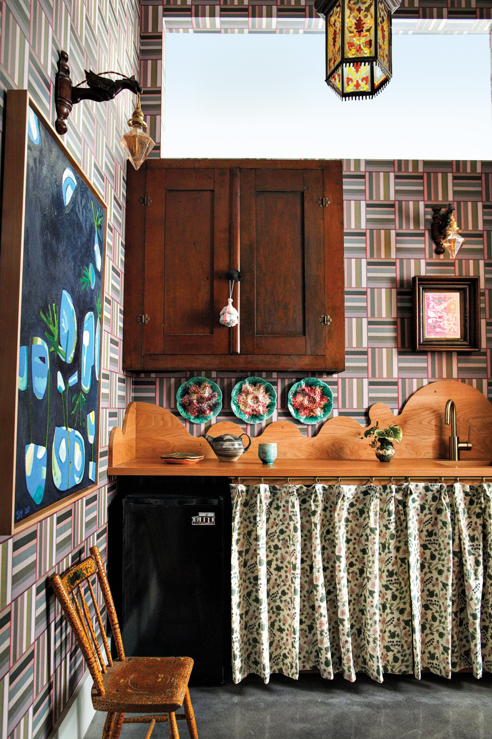 Kitchen space with geometric block-patterned wallpaper and a rustic dark wood floating cabinet