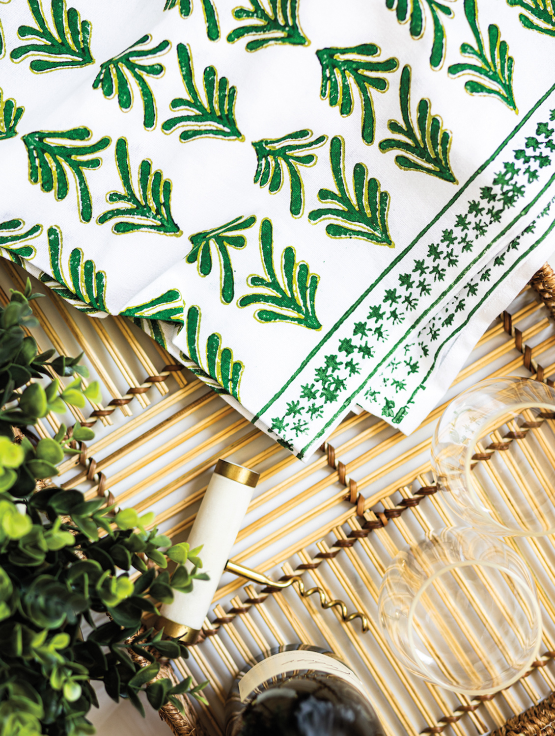 Wood-block printed table linens with a green and gold leafy pattern