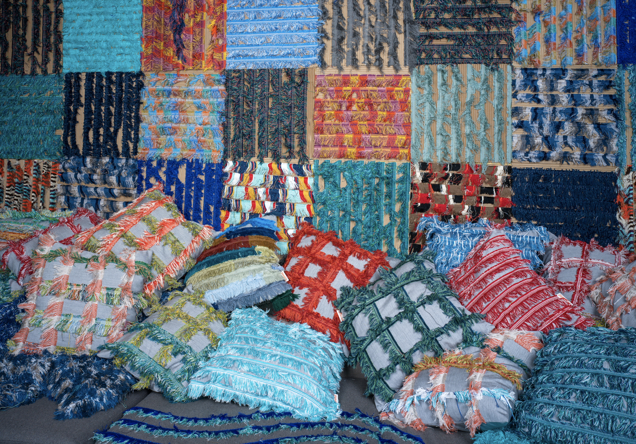colorful textiles on the wall match pillows lining the floor at a Milan Design Week 2024 exhibition