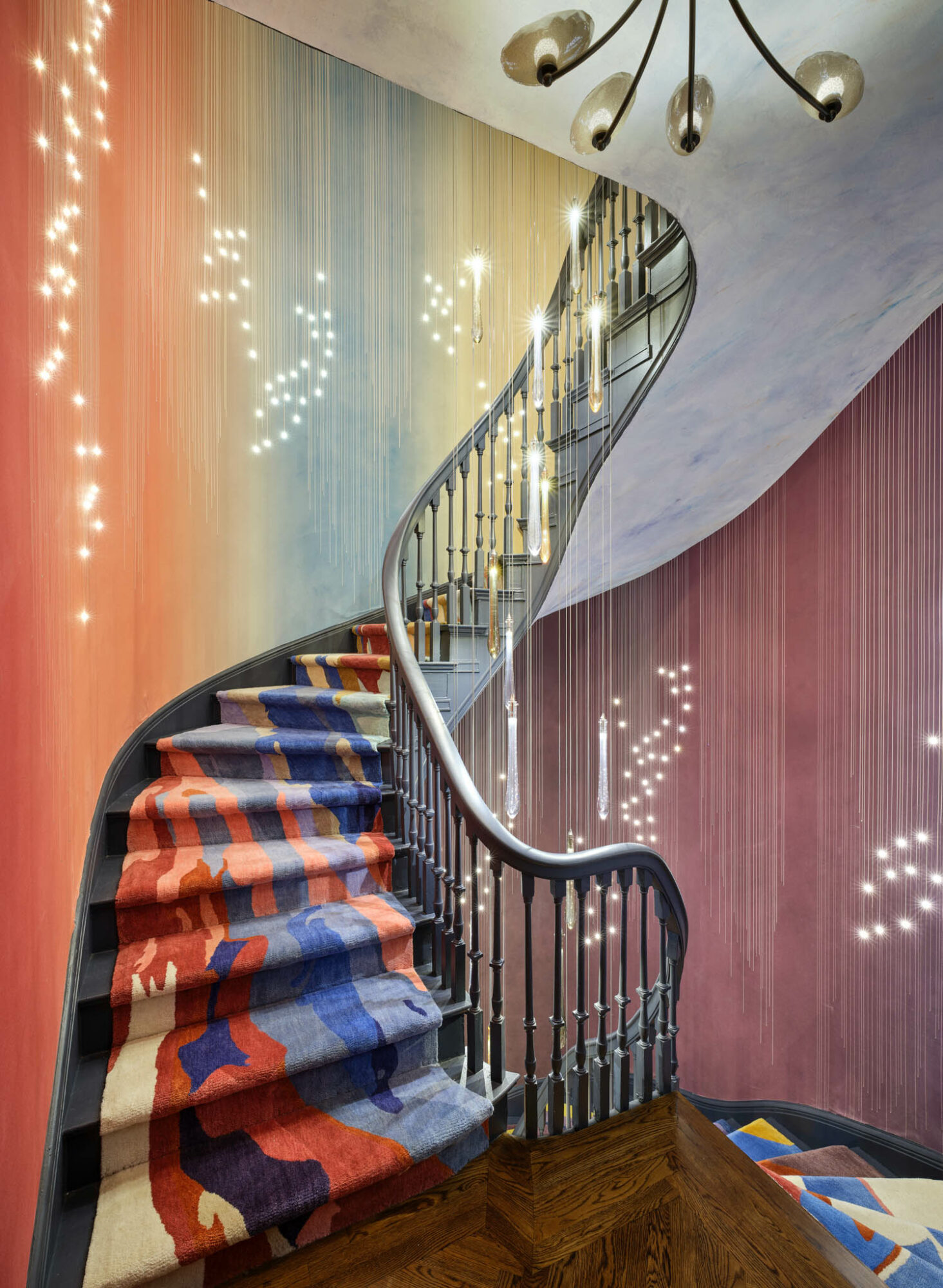 colorful rug lines a staircase with soft lights dangling above the railing