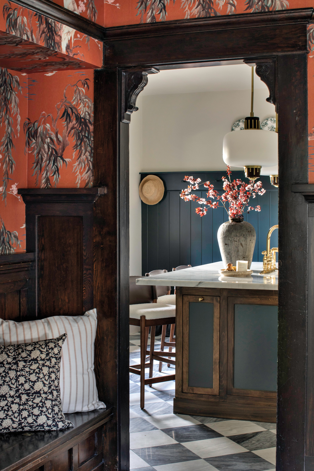 bar seen through an arch with dark-wood moldings with a patterned orange wallpaper surrounding it