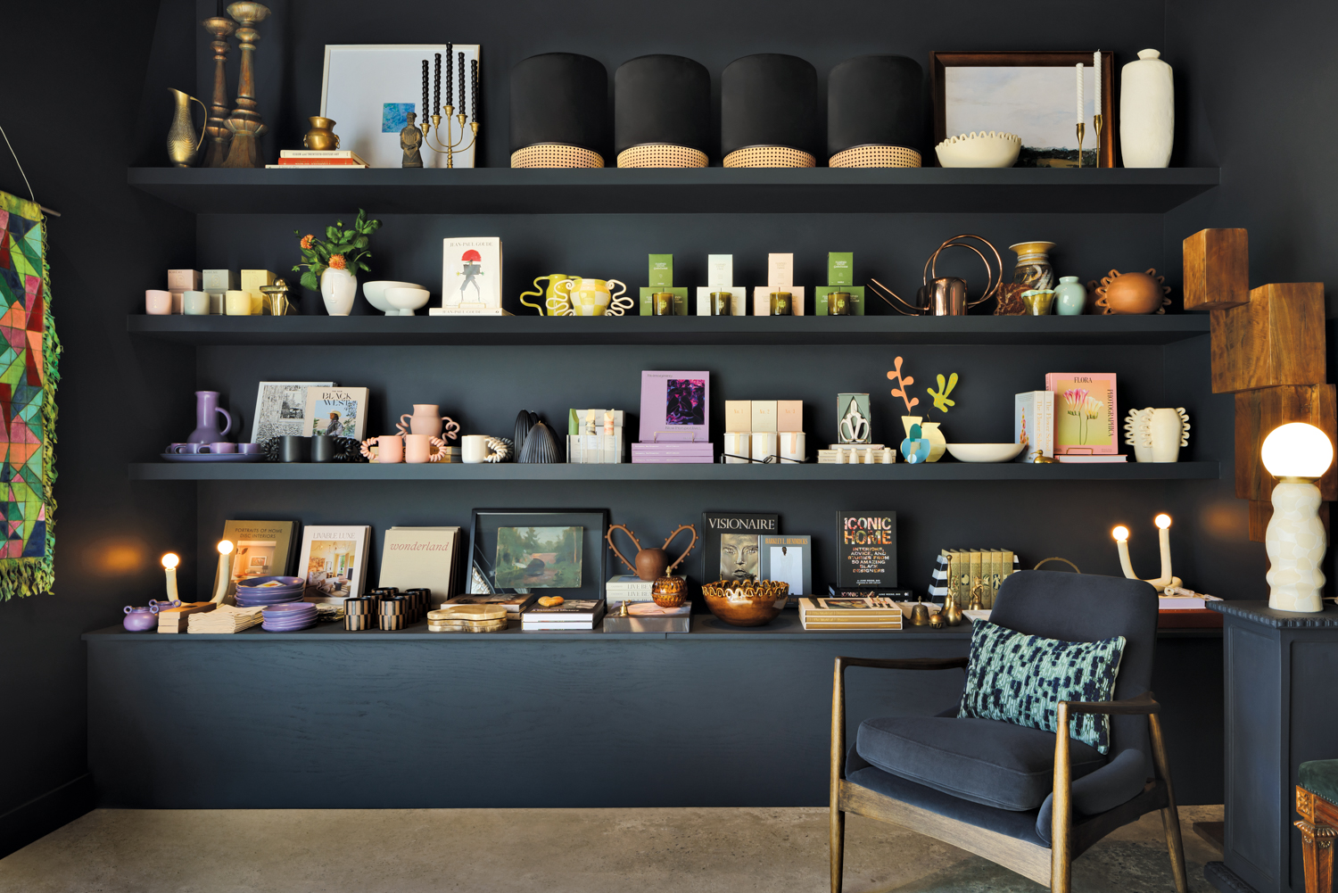 A variety of home decor goods on display on a black wall with floating black shelves.