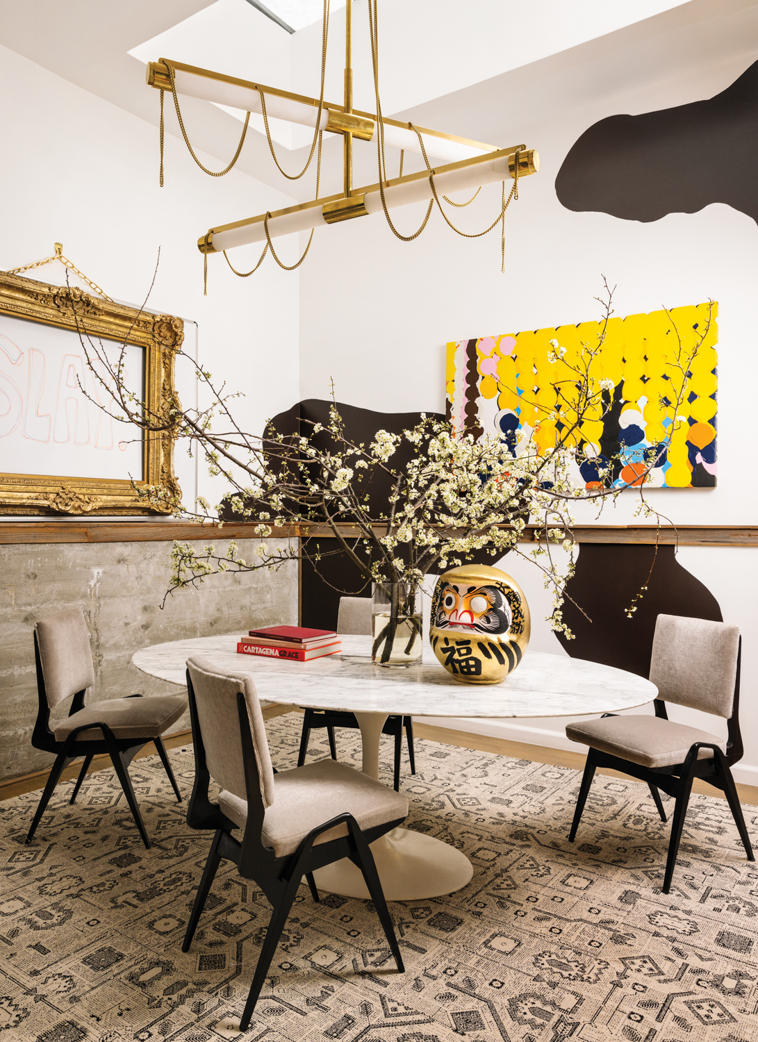 Dining room with upholstered chairs, marble oval table and gold chandelier with chain accents