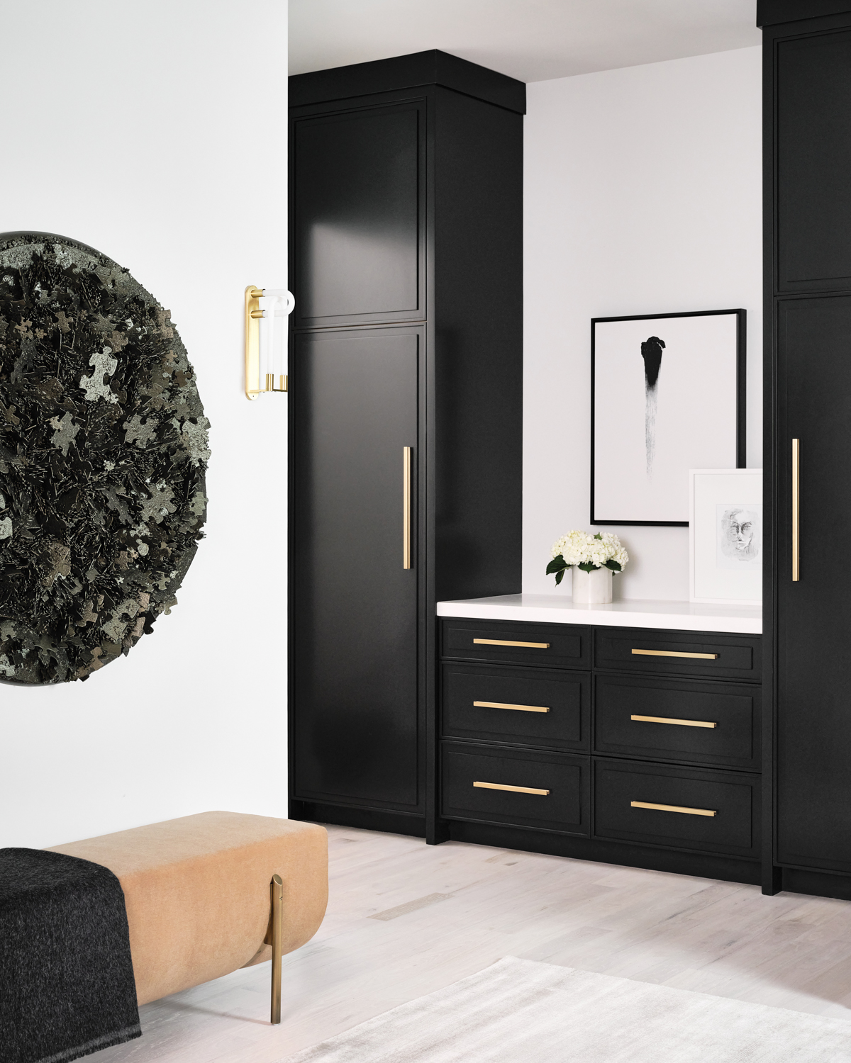 Mudroom with black cabinetry, brass...
