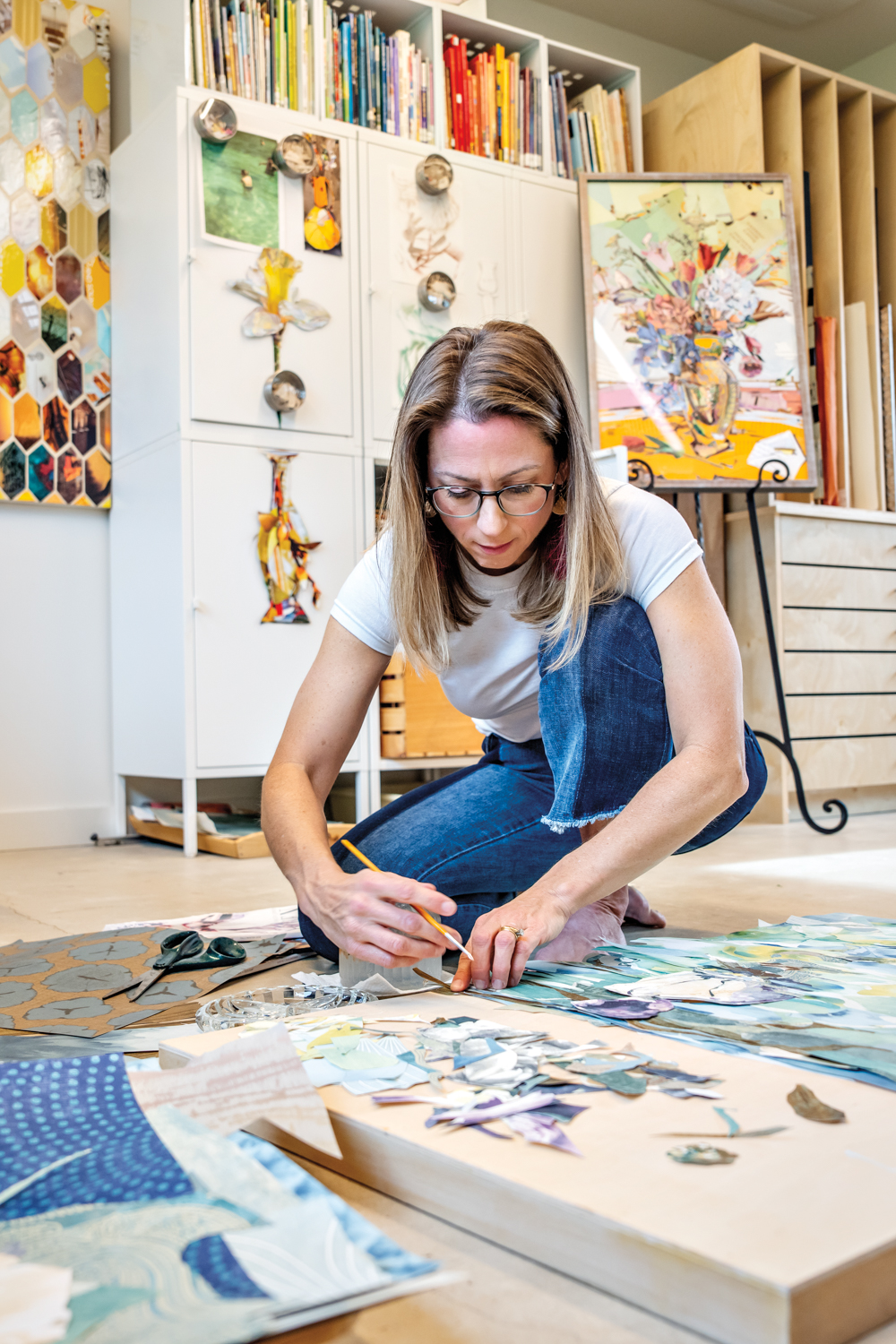 artist laurie carswell creating a collage on the floor
