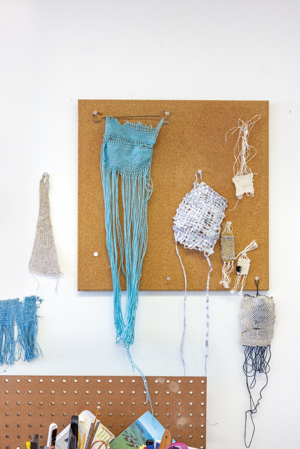 free form woven textiles hang on a corkboard
