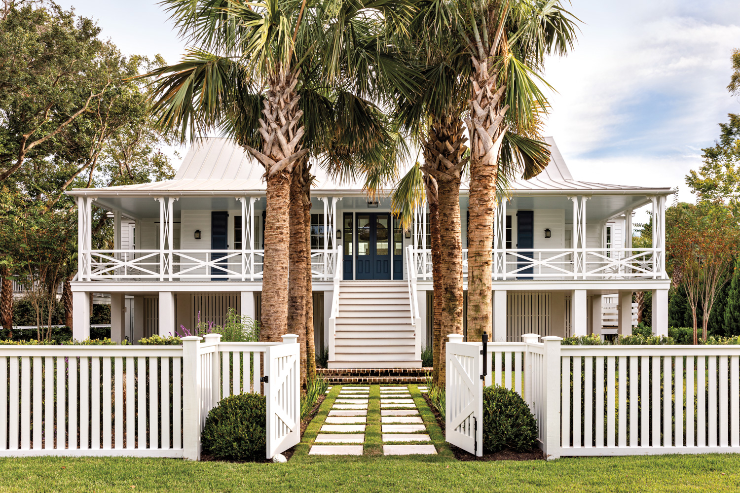 exterior of a beach house with palm trees lining the walkway to the front door