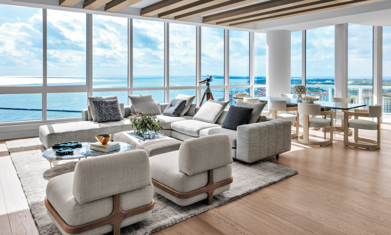 living area of high-rise with oceanfront views and low armchairs and sectional, and coffee tables