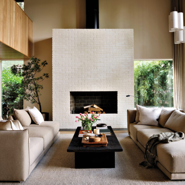 cozy living room with two neutral sofas, black coffee table and white brick fireplace