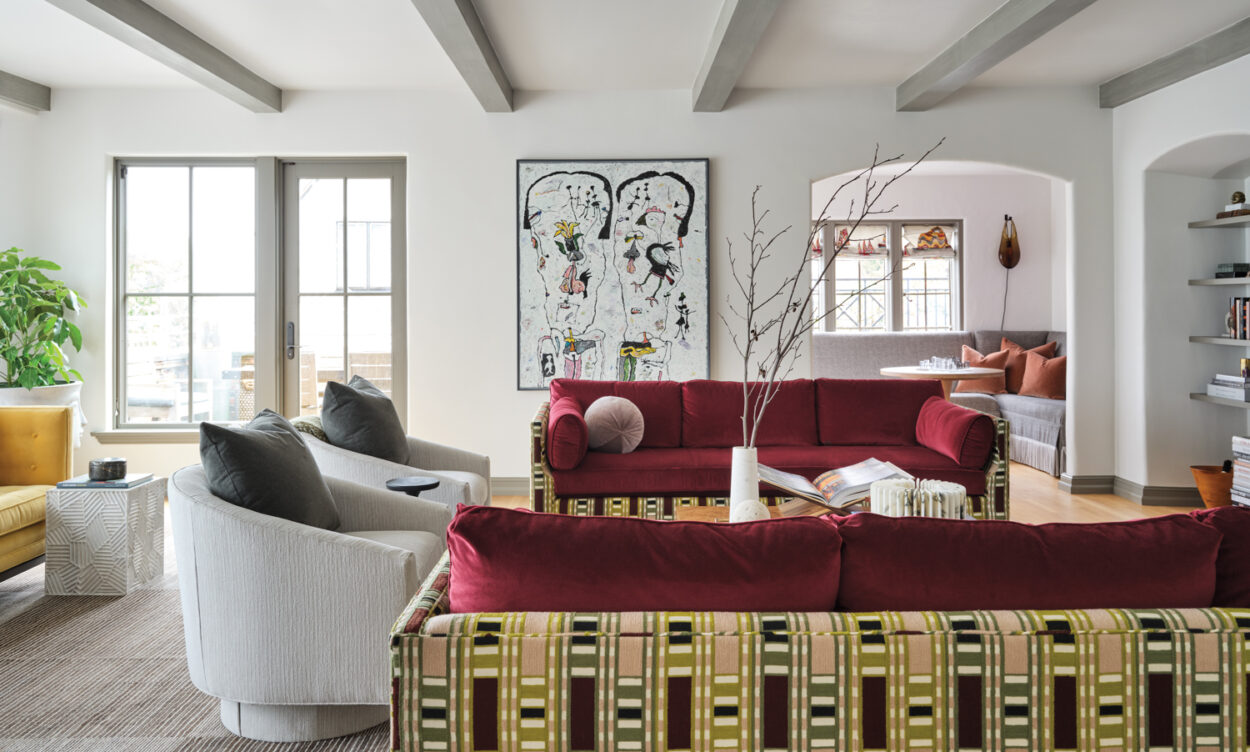 living area with colorful red sofas and patterned backing alongside grey armchairs