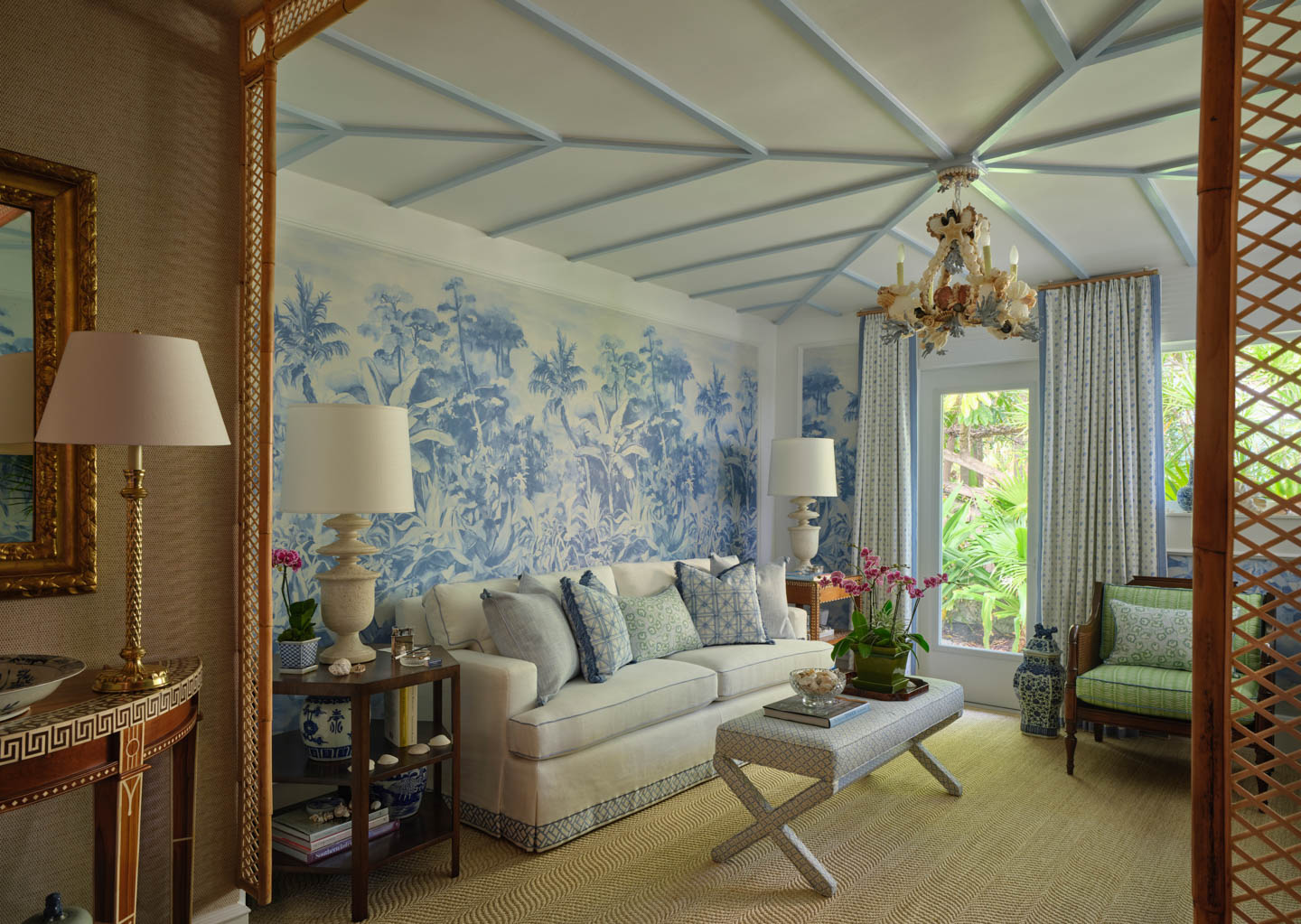 Elegant living room with a white sofa adorned with patterned cushions. A blue botanical mural covers the wall. 