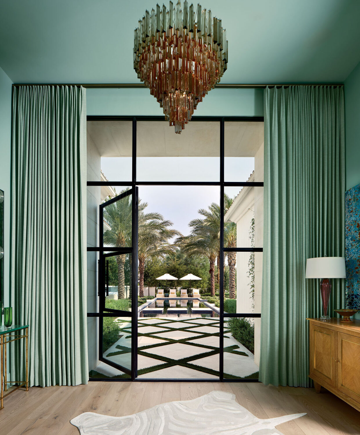 Luxurious entryway with tall glass doors opening to a lush garden beyond