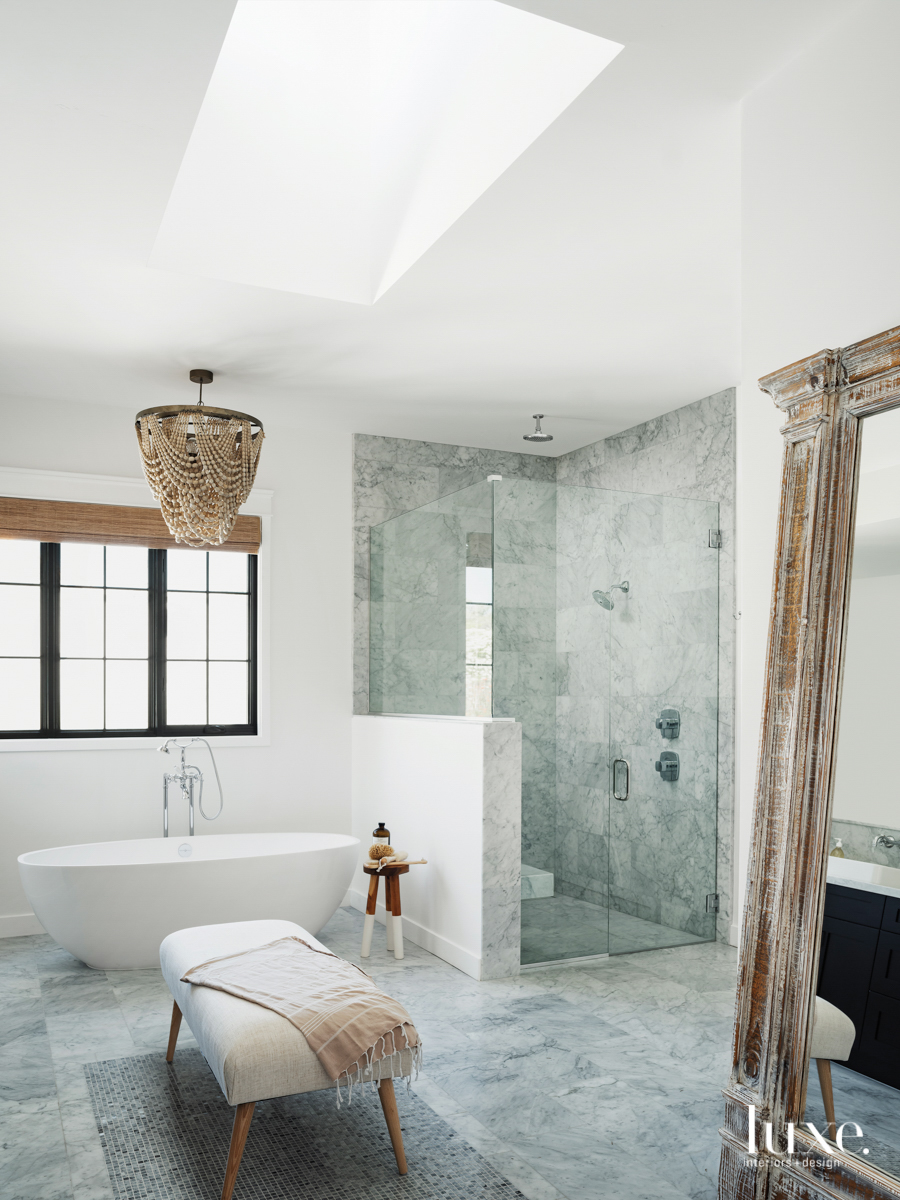 master bathroom with stone floors, a bench and stand alone tub