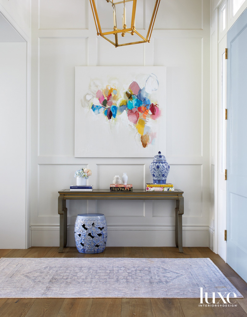 A foyer with a bright multi-color painting above a console.