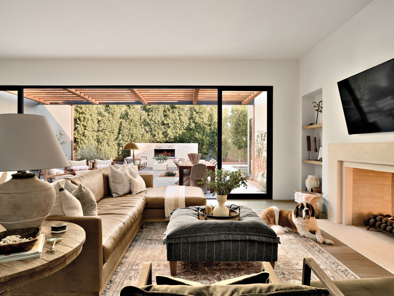 A Saint Bernard lays in a living room furnished with a pinstriped ottoman