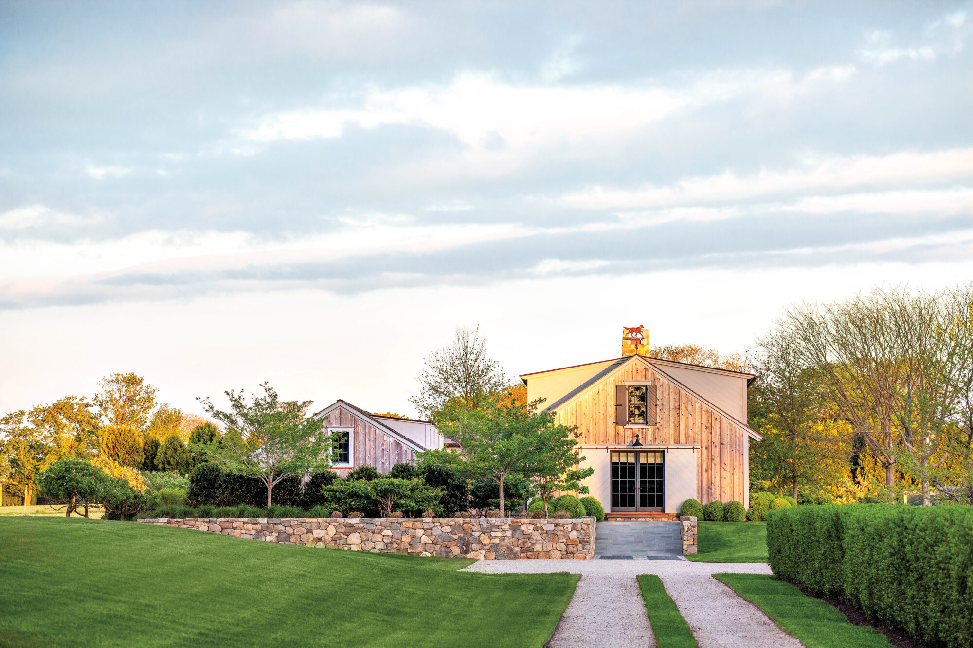 To celebrate the agrarian history of a family’s Bridgehampton property, Historical Concepts and Michael Davis Design & Construction envisioned a structure reminiscent of traditional potato barns in the area. Cedar board-and batten cladding and masonry details, including Connecticut fieldstone retaining walls and natural bluestone cleft slabs designed in tandem with Hollander Design Landscape Architects, speak to the old-meets-new ethos. exterior landscape and barn bridgehampton