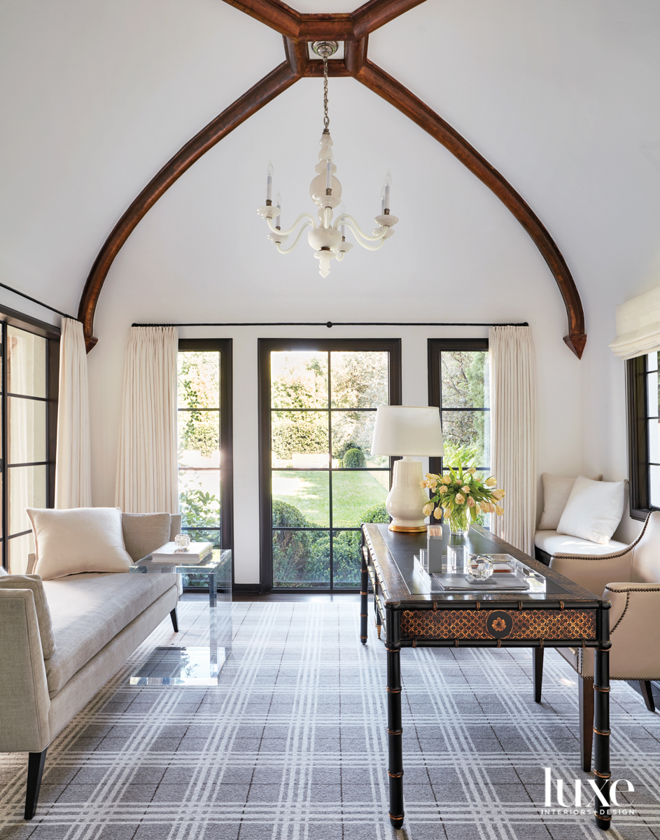 Office with vaulted ceiling, plaid carpet, desk and settee