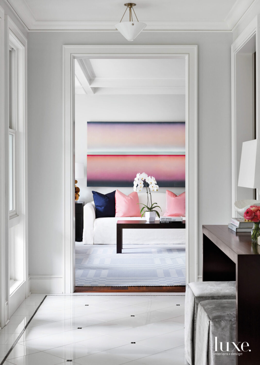 From the foyer you can see Into the living room where a pink-purple-and-blue painting by Casper Brindle hangs above the sofa.