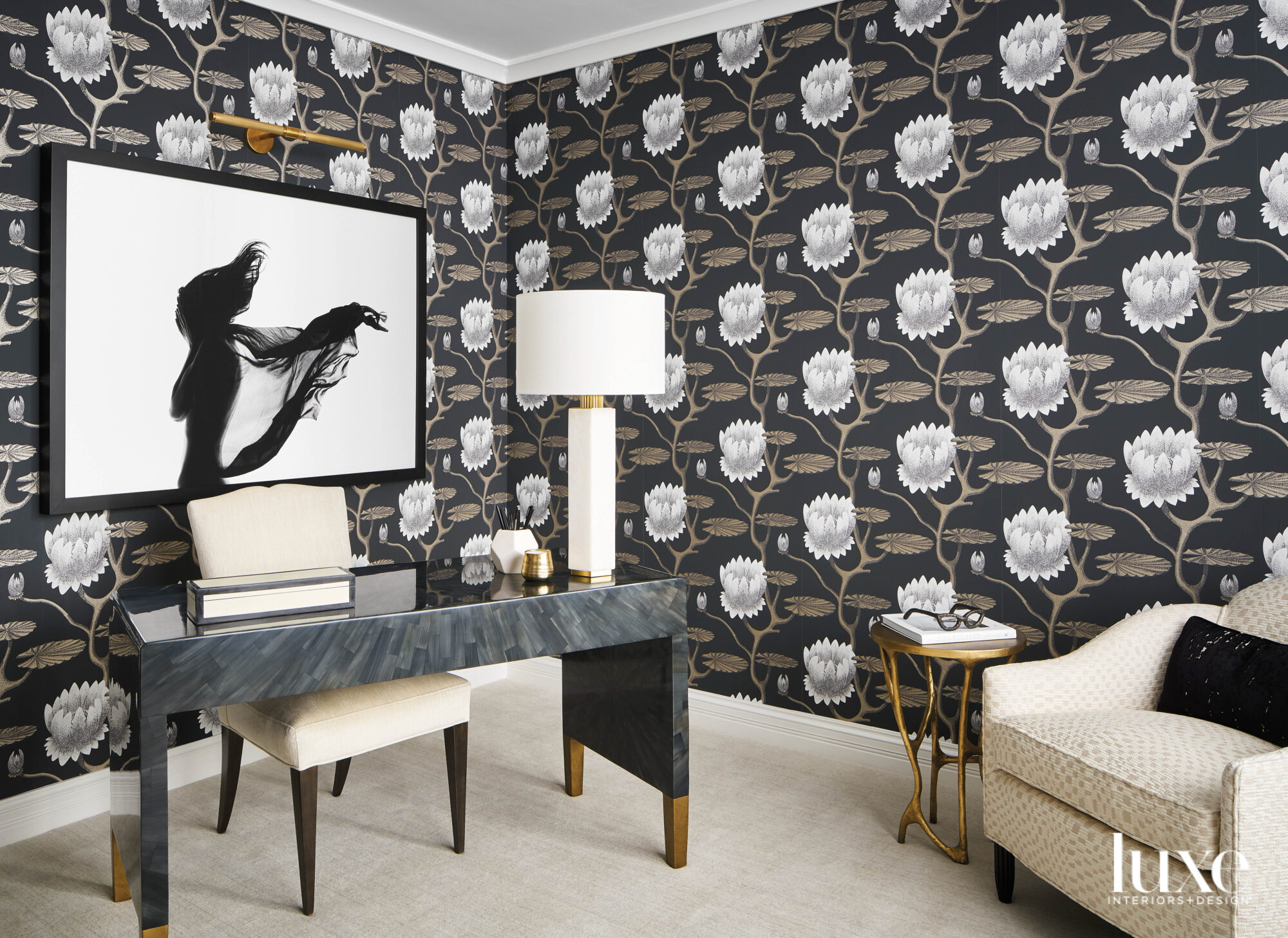 A home office has a dramatic floral wallpaper. A black-and-white photograph hangs behind the desk.