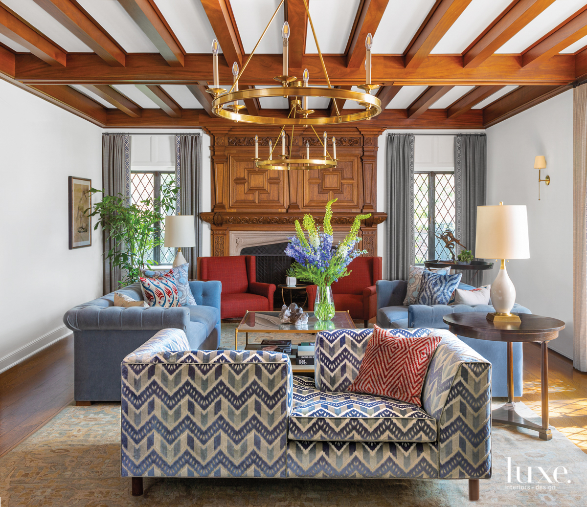 A living room is full of blue and berry tones, as well as pattern. A settee is at the front of the room.