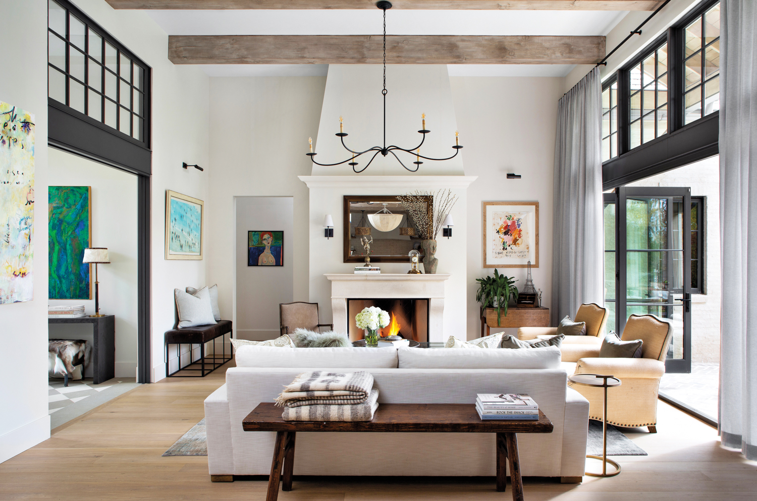 living room with a neutral sofa and antique English farm bench, with a black chandelier and wall art