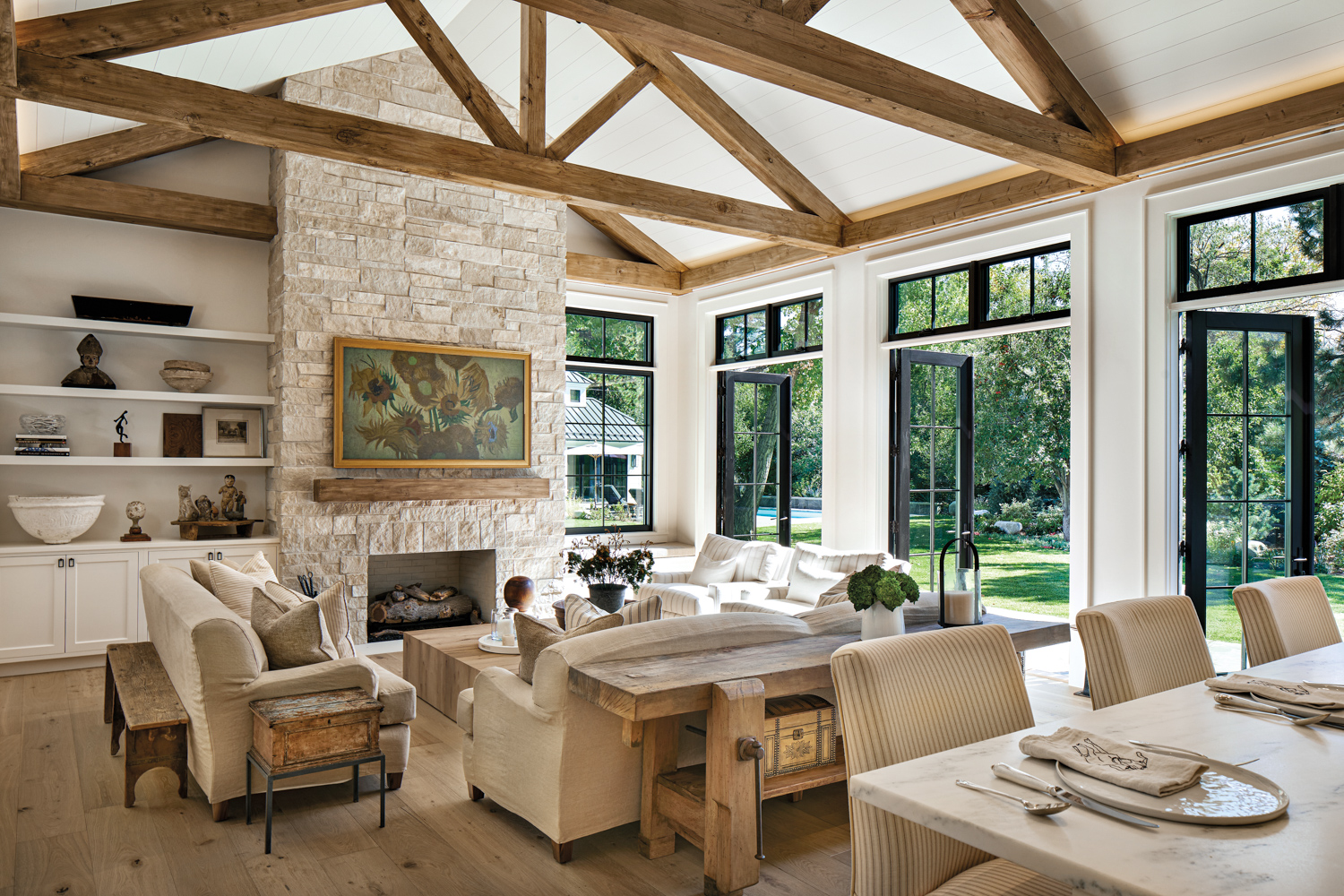 family room with timber trusses and a limestone fireplace surround