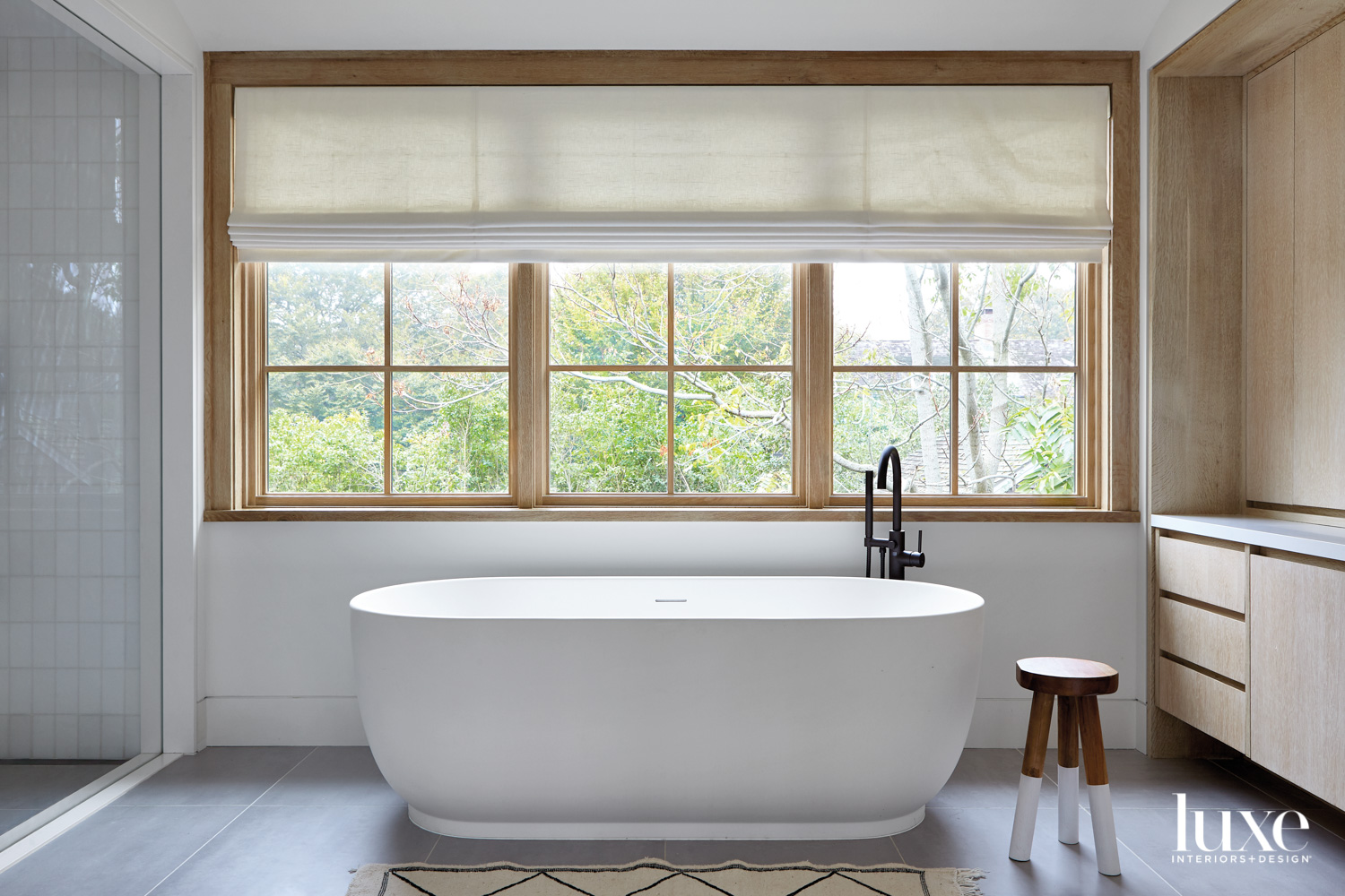 White soaking tub in front of large window