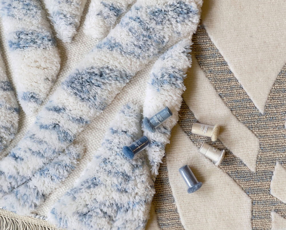 A blue-and-white patterned rug and a white-and-gray patterned rug layered on top of one another.