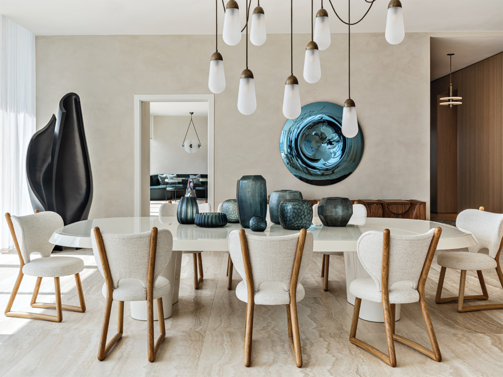 modern white dining room with Apparatus’ Lariat pendants above the table and a blue mirrored artwork