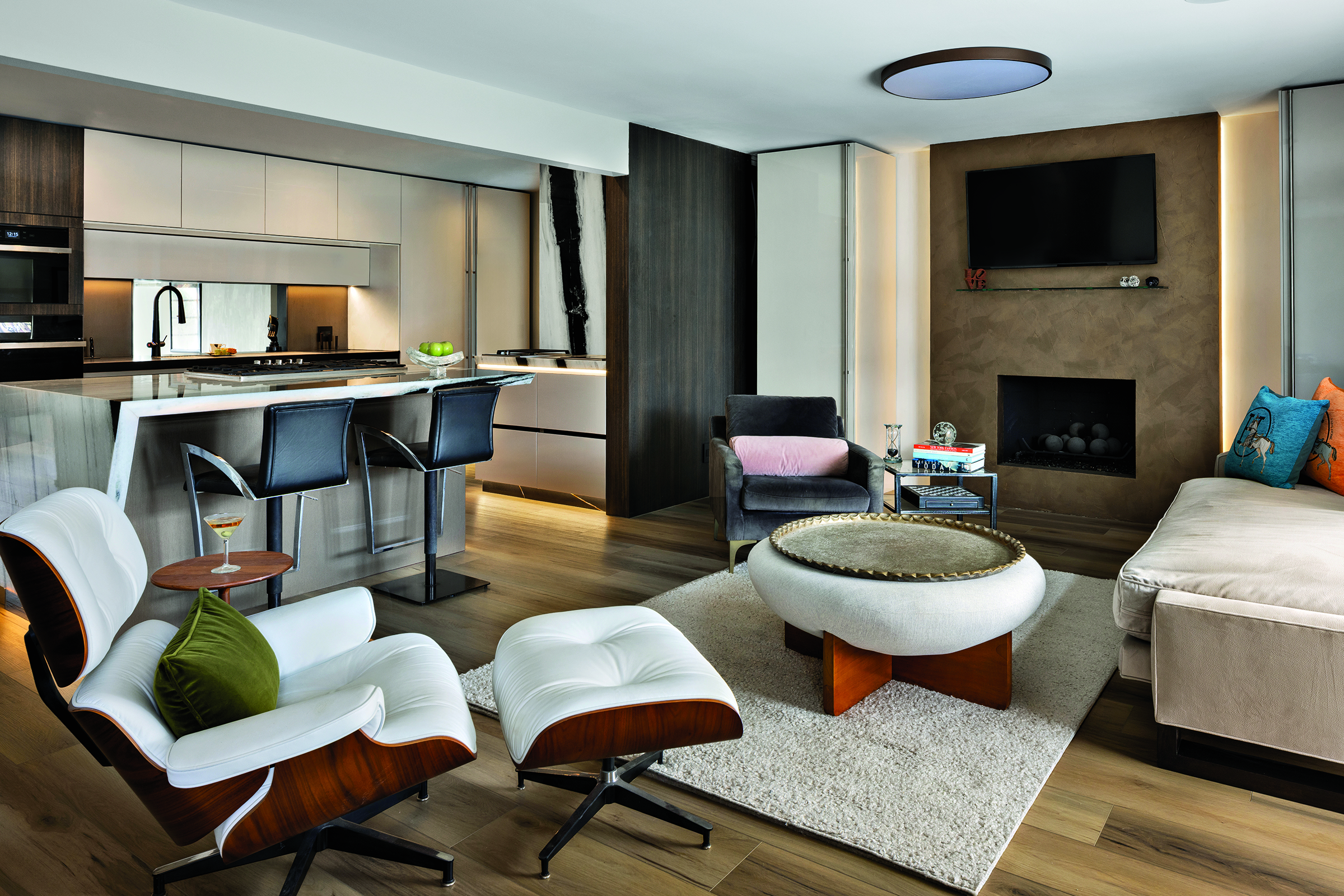 Wide view of the Pazzam Project kitchen by Pazzam Designs, showcasing a sculptural island, integrated cabinetry, and dramatic light-and-shadow contrast inspired by chiaroscuro principles.
