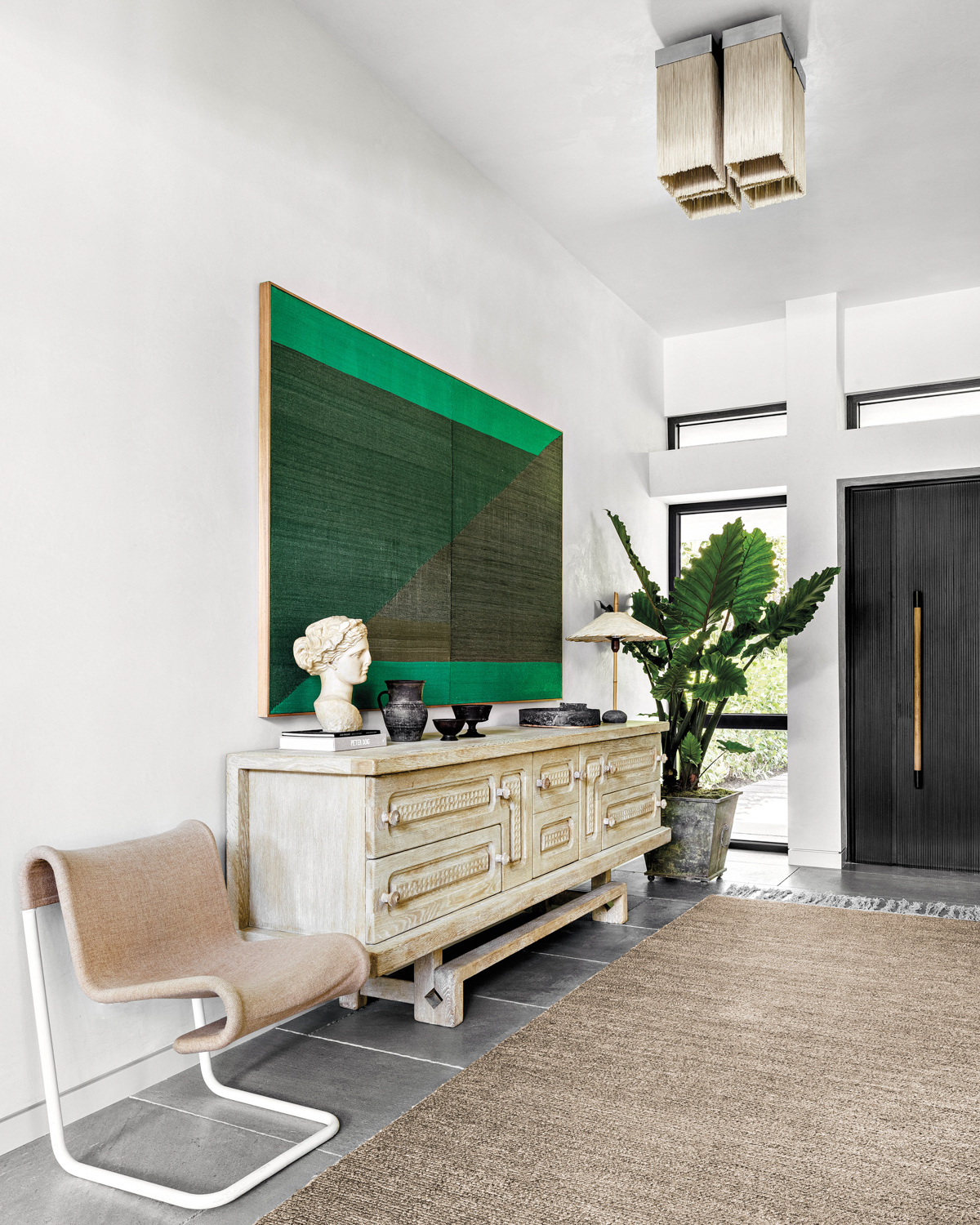 hallway with green painting, white drawers, bench and statue bust in home by Constanza Collarte