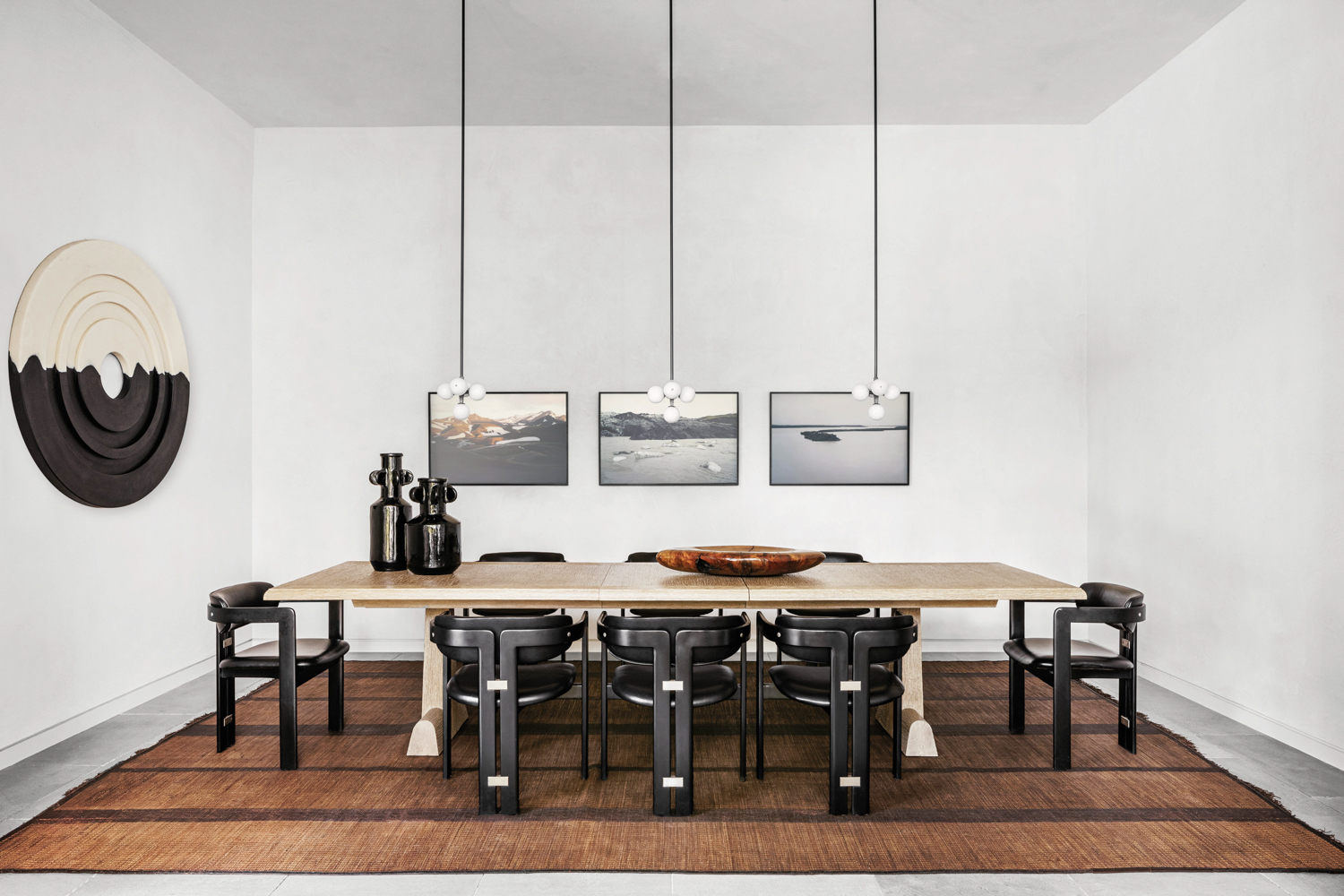 dining room with photographs, long table, black dining chairs in home by Costanza Collarte