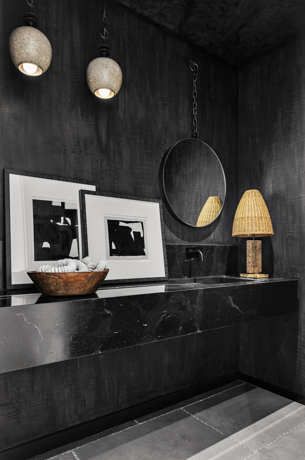 black powder room with photographs, mirror and rattan lamp in home by Costanza Collarte
