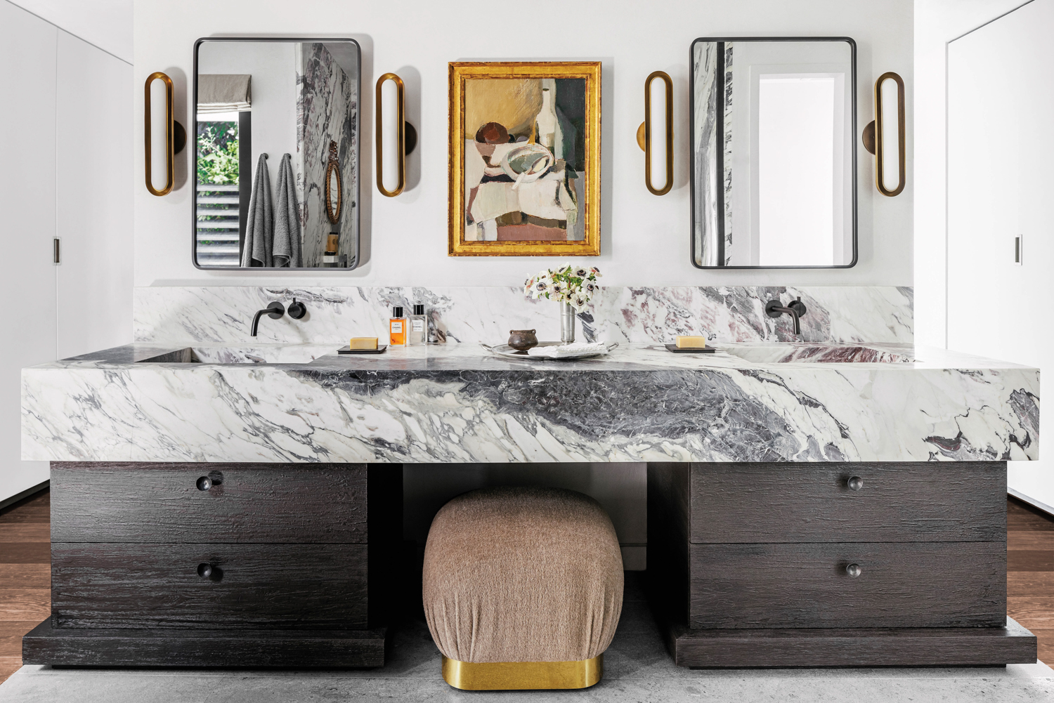 bathroom with dual mirrors, marble countertop, painting and pink pouf in home by Costanza Collarte