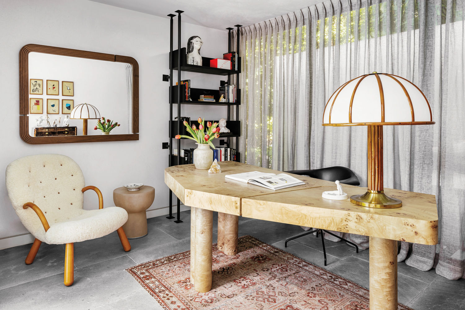 study with wooden table, lamp, red rug and black shelving in home by Costanza Collarte