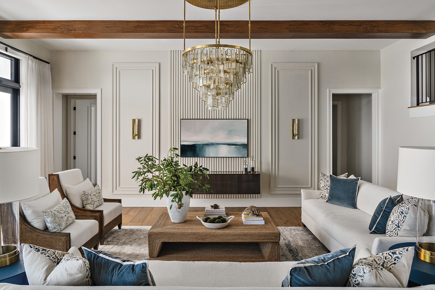Elegant living room with white sofas, blue cushions, and wicker armchairs