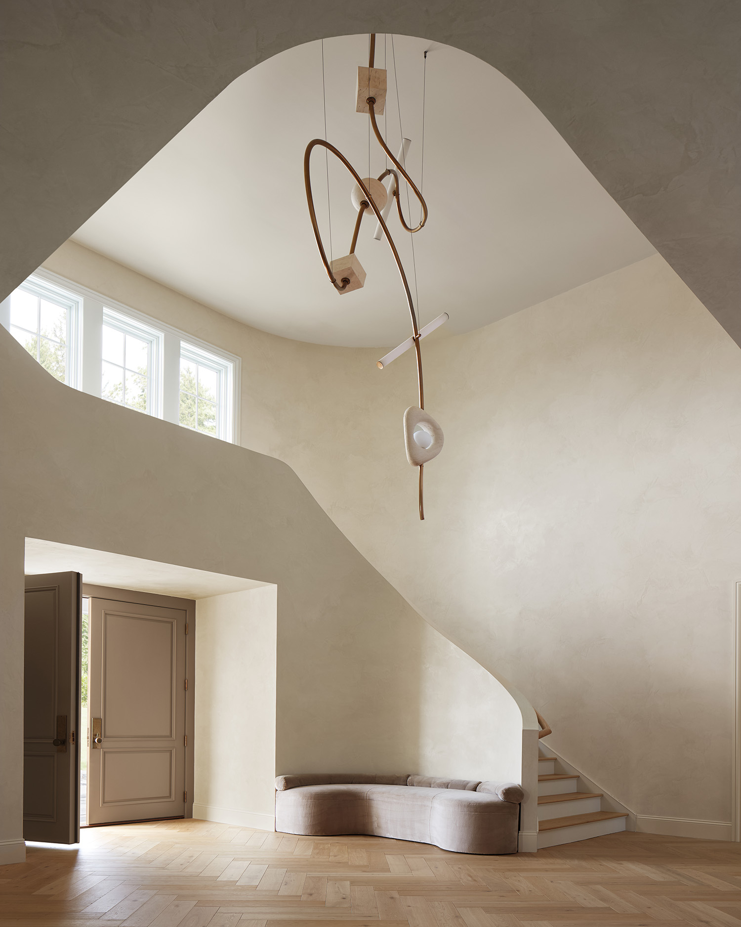 Anna Karlin light fixture in an entry with limestone Venetian plaster walls by Katie DuBree.