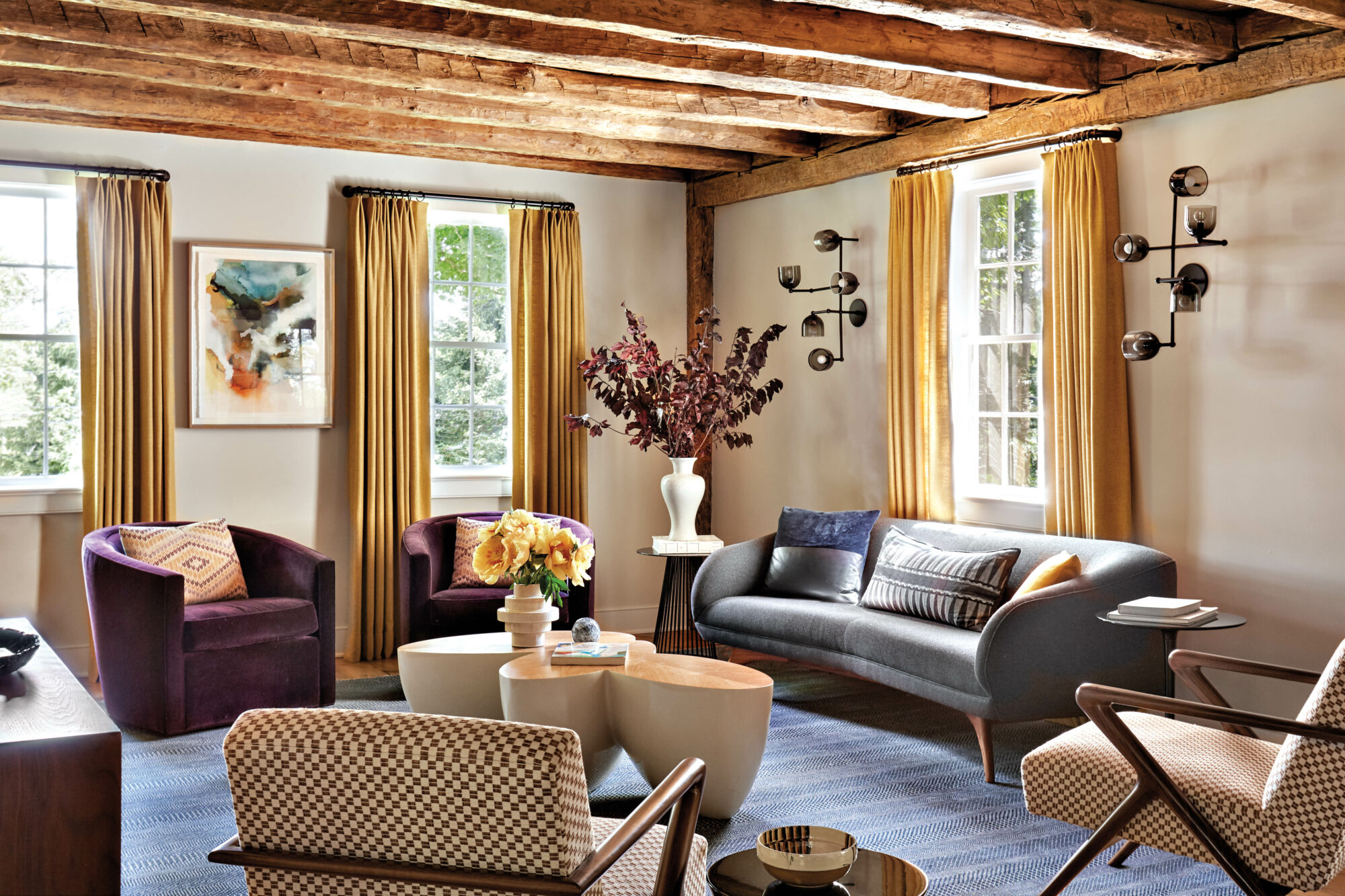 sofa and wooden coffee table under chandelier and vintage photograph in living room by Sondra Ganz