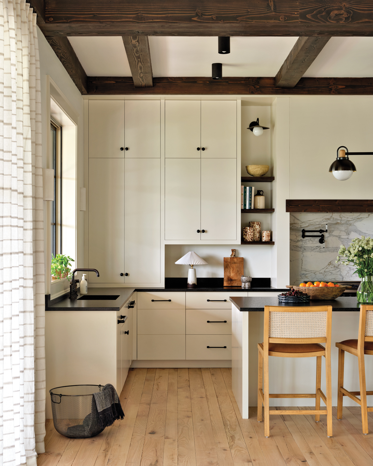 White kitchen with leather granite countertops, wooden stools and sconces