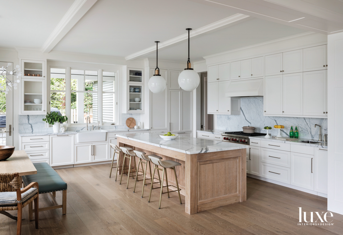 white kitchen with wood island and globe pendants
