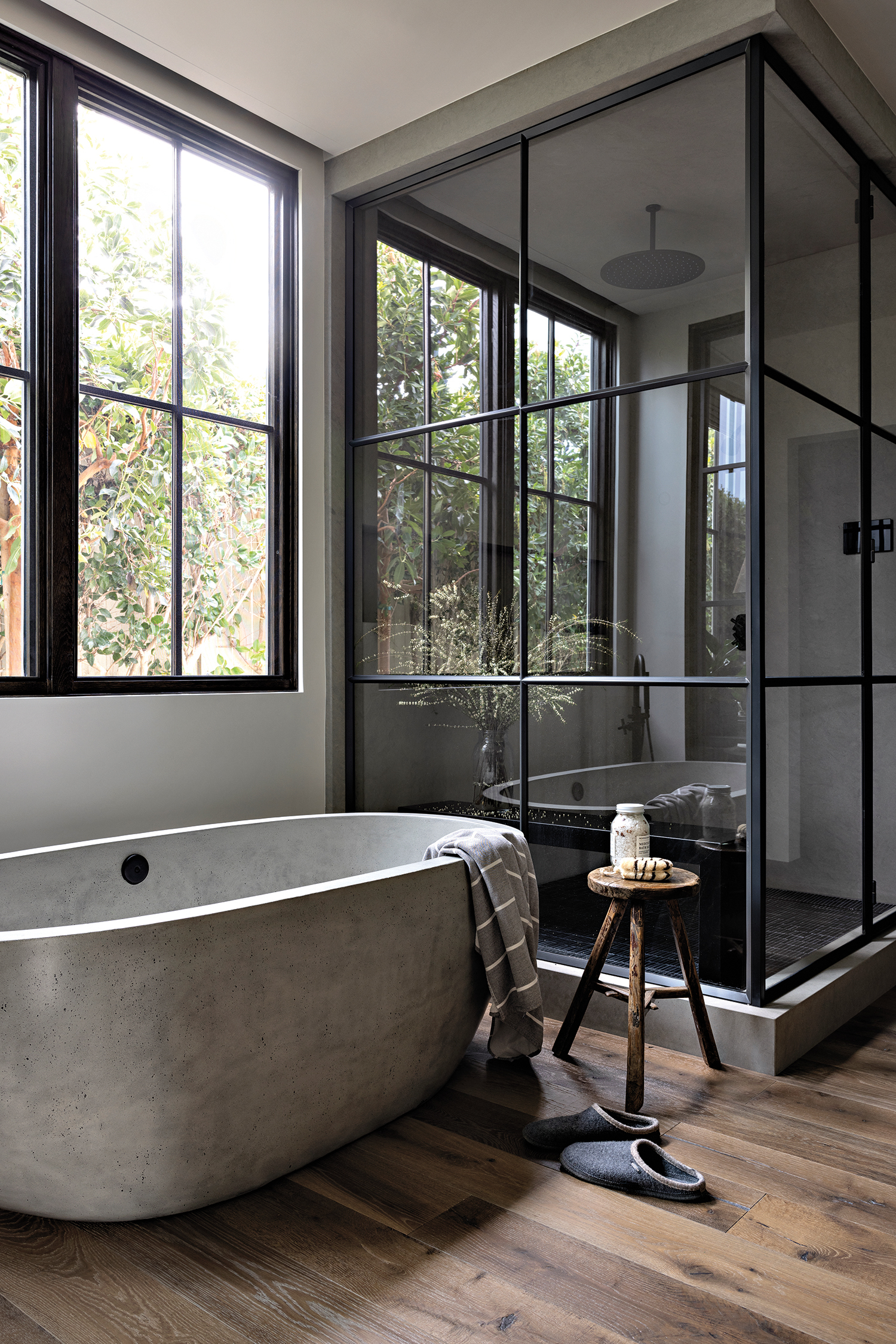 modern neutral bathroom with a concrete bathtub and a steel and glass shower