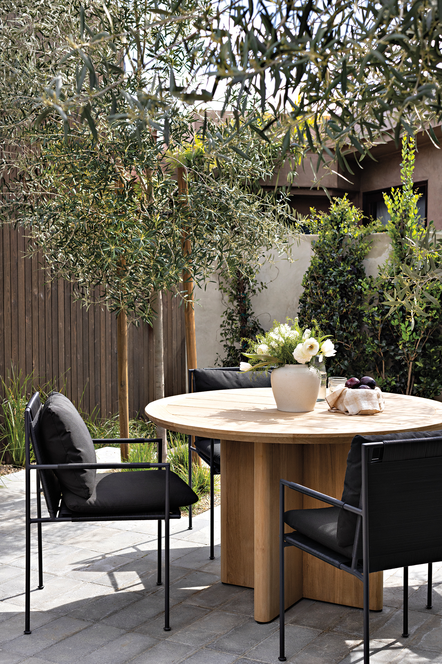 a teak dining table on the patio of a modern California home