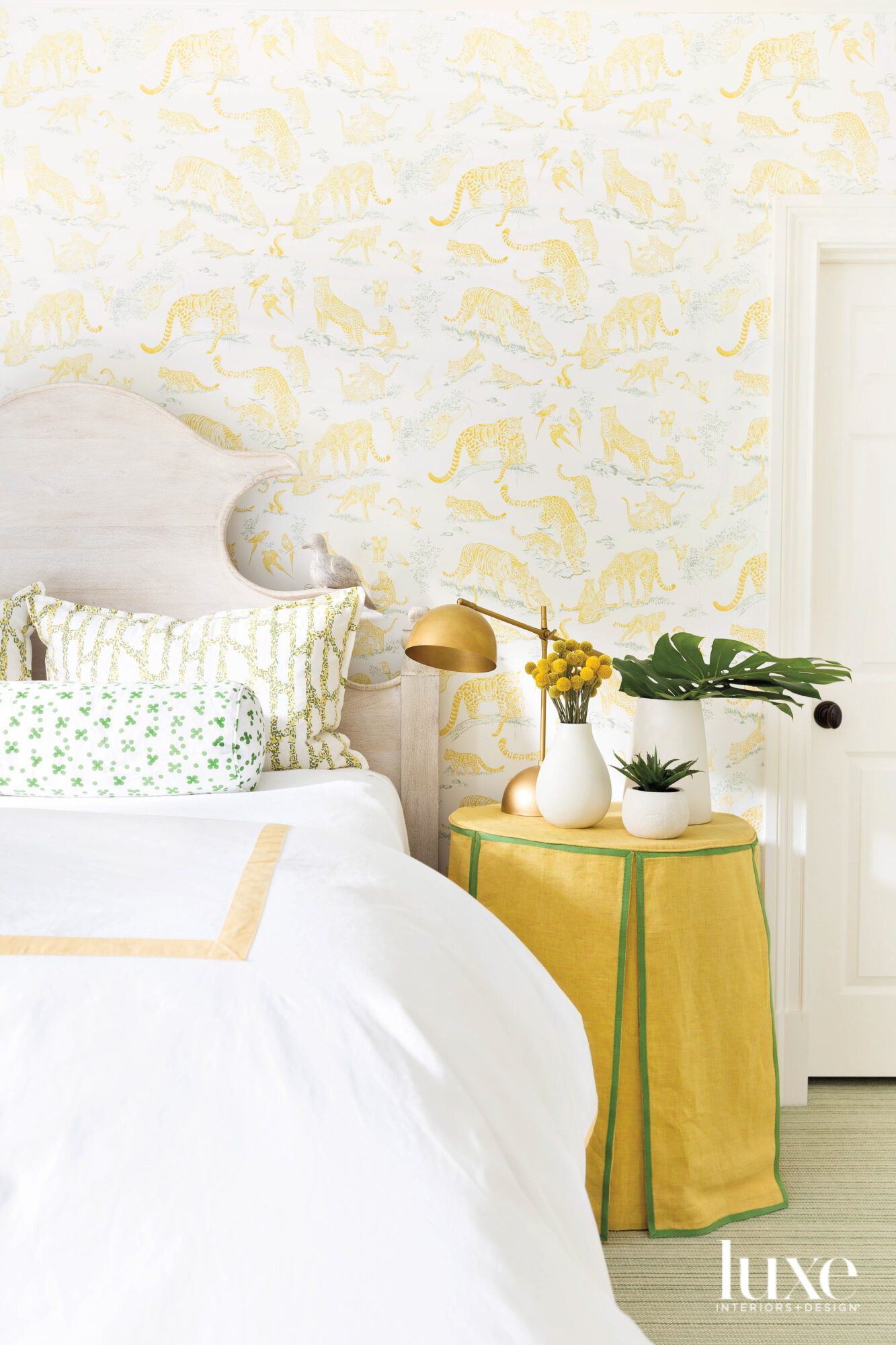 Photo of bed with yellow wallpaper and yellow skirted table