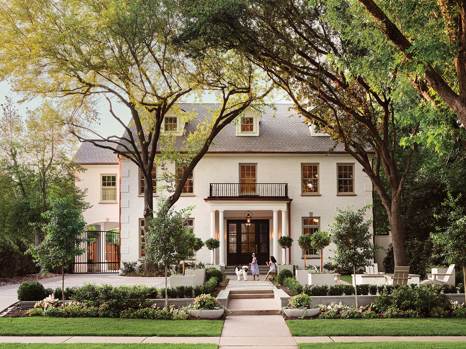 Georgian-style home exterior in white surrounded by tall trees