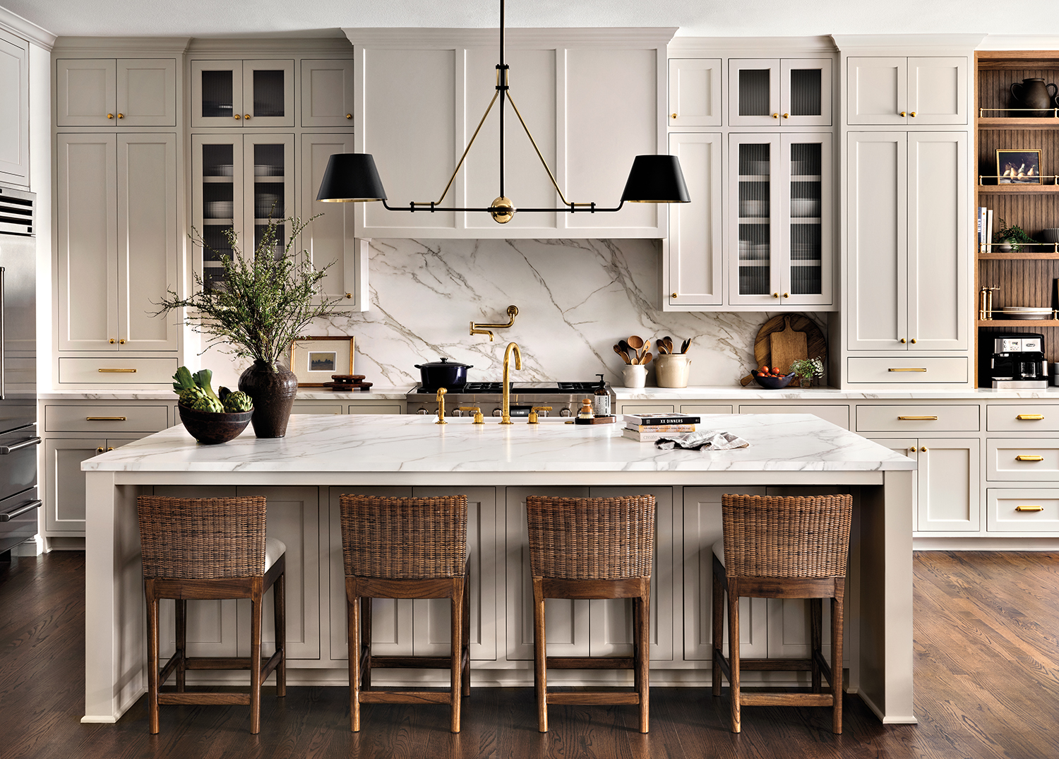 traditional kitchen with white cabinetry and woven barstools pulled up to an island