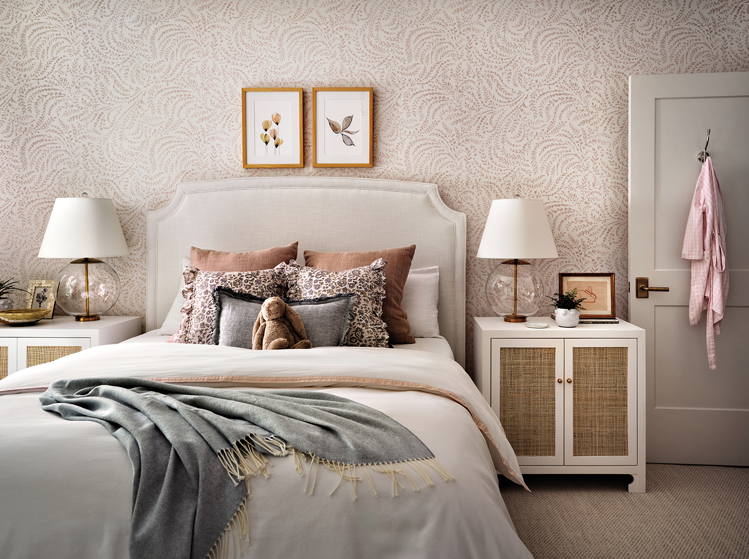 young girl's bedroom with an upholstered grey bed and floral pink and white wallpaper
