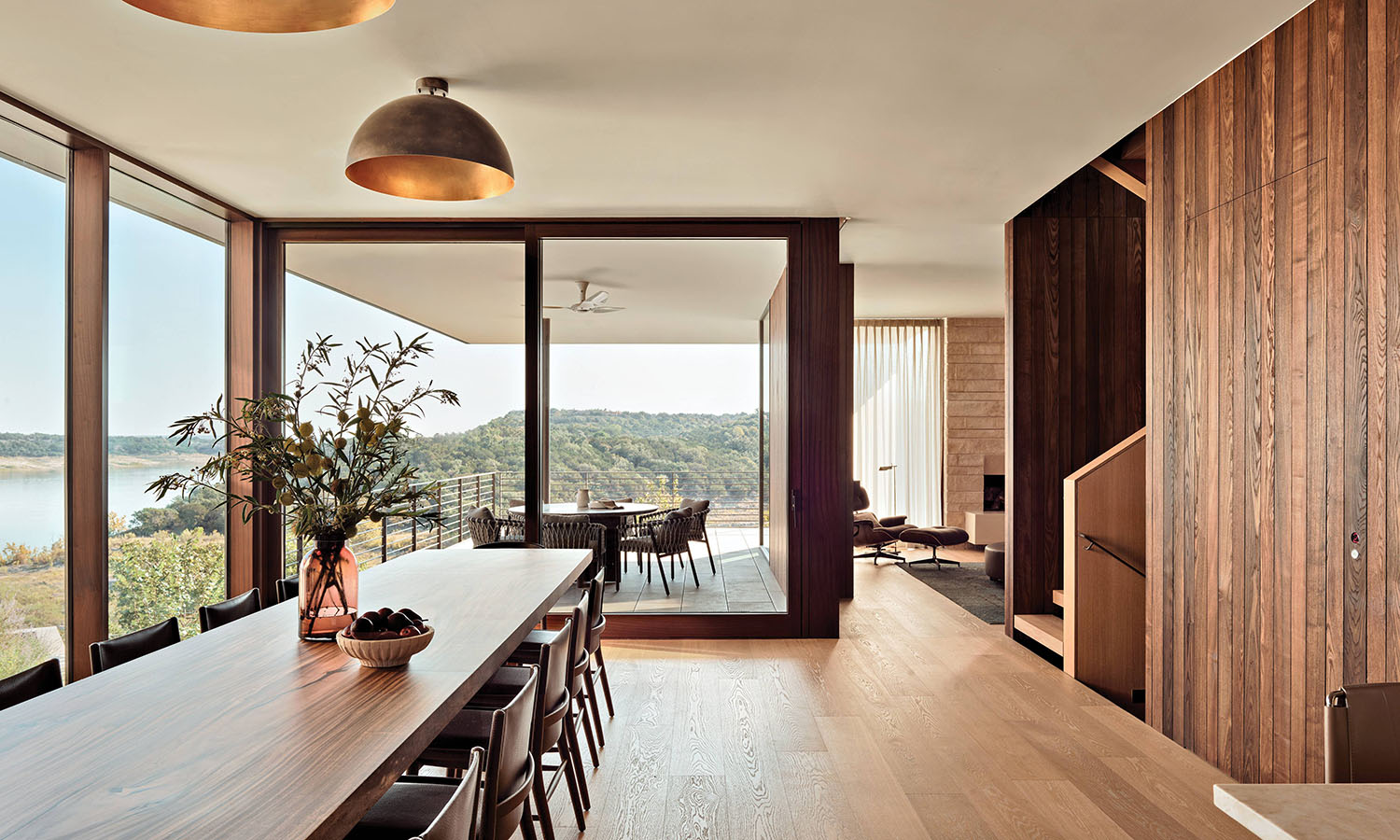 oak floored dining room with a long family table and glass walls
